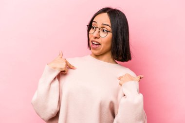 Pembe arka planda izole edilmiş genç İspanyol kadın parmağını gösterip geniş bir gülümsemeyle şaşırdı..