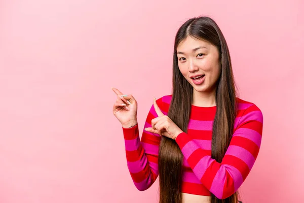 年轻的中国女人被粉色背景隔离 食指指向一个复制空间 表达兴奋和渴望 — 图库照片
