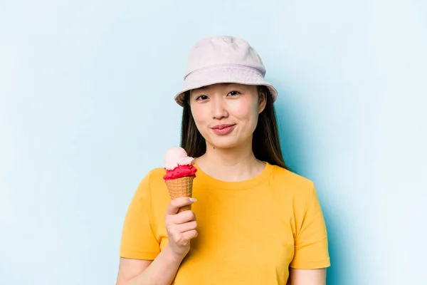 年轻的亚洲女人吃着蓝色背景的冰淇淋 — 图库照片