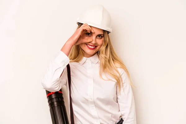 Young architect woman with helmet and holding blueprints isolated on white background excited keeping ok gesture on eye.