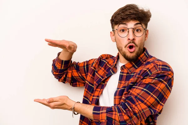 Beyaz arka planda izole edilmiş genç İspanyol adam elleri arasında bir kopya alanı tutarken şok ve hayrete düştü..