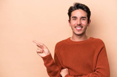 Beyazların arka planında izole edilmiş genç beyaz adam işaret parmağıyla işaret ederek gülümsüyor..