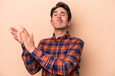 Beyaz tenli genç adam bej arka planda izole edilmiş enerjik ve rahat hissediyor, ellerini ovuşturuyor kendinden emin..