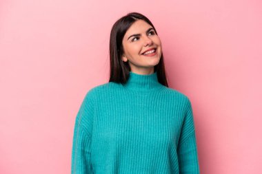 Genç beyaz kadın pembe arka planda izole edilmiş rahat ve mutlu bir şekilde gülüyor, boynunda dişlerini gösteriyor..