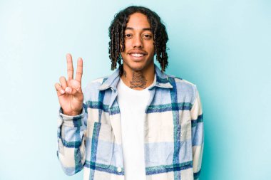 Genç Afrikalı Amerikalı adam mavi arka planda izole edilmiş zafer işareti gösteriyor ve gülümsüyor..