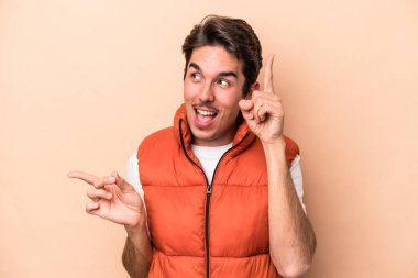 Beyazların arka planında izole edilmiş genç beyaz adam farklı kopya alanlarını gösteriyor, birini seçiyor, parmaklarıyla gösteriyor..