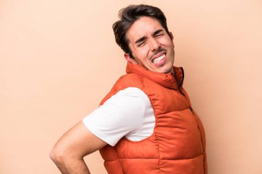 Bej arka planda izole edilmiş beyaz bir adam sırt ağrısı çekiyor..