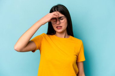 Kafkasyalı genç bir kadın mavi arka planda izole edilmiş, başı ağrıyor, yüzüne dokunuyor..