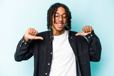 Mavi arka planda izole edilmiş genç bir Afrikalı Amerikalı gururlu ve kendinden emin hissediyor..