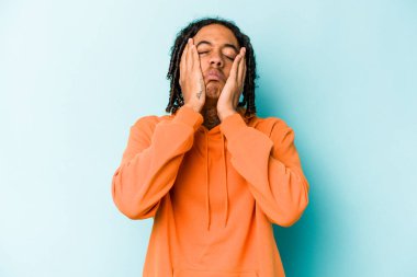 Genç Afro-Amerikalı adam mavi arka planda yalnız başına sızlanıyor ve ağlıyordu..