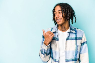 Genç Afrikalı Amerikalı adam mavi arka plan noktalarında izole edilmiş, başparmak uzakta, gülüyor ve kaygısız..