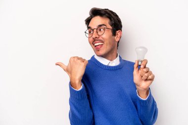 Beyaz arka planda bir ampul tutan beyaz tenli genç adam parmak uzakta, gülüyor ve kaygısız..