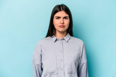 Genç beyaz kadın mavi arka planda izole edilmiş üzgün, ciddi yüzlü, mutsuz ve hoşnutsuz..