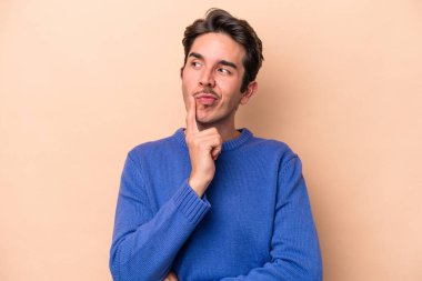 Beyazlı genç bir adam bej arka planda izole edilmiş. Bir strateji planlıyor, bir iş yolu düşünüyor..