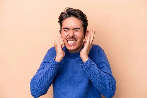 Hombre Joven Caucásico Aislado Sobre Fondo Beige Cubriendo Las Orejas — Foto de Stock