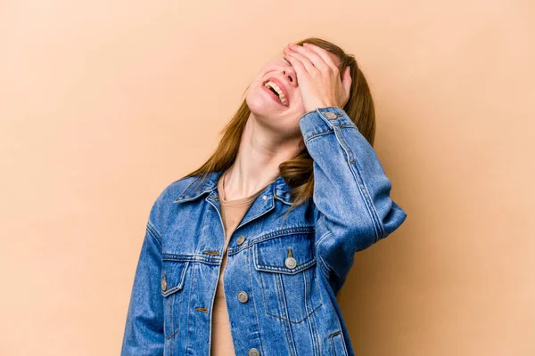 Young English woman isolated on beige background laughs joyfully keeping hands on head. Happiness concept.