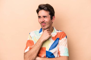 Beyazlı genç bir adam bej arka planda virüsten ya da enfeksiyondan boğaz ağrısı çekiyor..