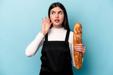 Genç fırıncı Kafkas elinde bir somun ekmekle mavi arka planda bir dedikoduyu dinlemeye çalışıyor..