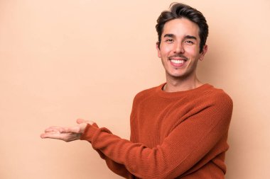 Beyaz tenli genç, bej arka planda izole edilmiş. Elinde palmiye ağacında bir fotokopi alanı var..
