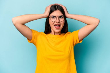 Mavi arka planda izole edilmiş genç beyaz kadın çığlık atıyor, çok heyecanlı, tutkulu, bir şeyden memnun..