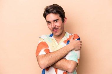 Beyaz tenli genç adam bej arka planda izole edilmiş, gülümsüyor ve mutlu..