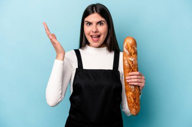 Mavi arka planda izole edilmiş bir somun ekmek tutan genç fırıncı heyecanlı ve el kaldıran hoş bir sürpriz alıyor..