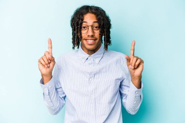 Mavi arka planda izole edilmiş genç Afrikalı Amerikalı iki parmağı da boş bir alan gösteriyor..
