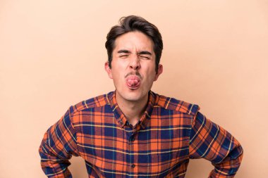 Beyazlı genç bir adam bej arka planda izole edilmiş komik ve dost canlısı bir dil kullanıyor..