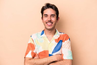 Beyazların arka planında izole edilmiş genç, kendinden emin, kararlılıkla kollarını kavuşturan bir adam..