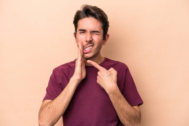 Beyazlı genç bir adam bej arka planda izole edilmiş güçlü bir diş ağrısı ve azı dişi ağrısı var..