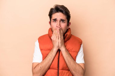 Beyazlı genç bir adam bej arka planda izole edilmiş ağzı kapalı ve elleri endişeli görünüyor..