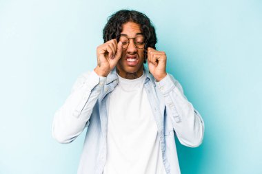 Genç Afro-Amerikalı adam mavi arka planda yalnız başına sızlanıyor ve ağlıyordu..