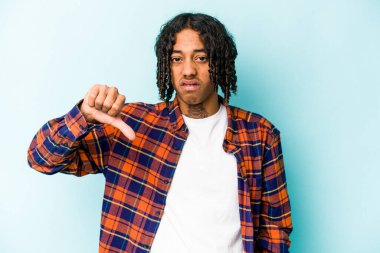 Genç Afro-Amerikalı adam mavi arka planda izole edilmiş, baş parmağını aşağı gösteren, hayal kırıklığı konsepti.