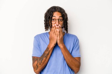 Beyaz arka planda izole edilmiş genç Afrikalı Amerikalı adam elleriyle ağzını kapatırken şok oldu..
