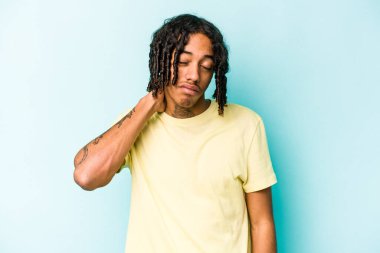 Genç Afrikalı Amerikalı erkek mavi arka planda izole edilmiş. Stres yüzünden boynu ağrıyor, masaj yapıyor ve elle dokunuyor..