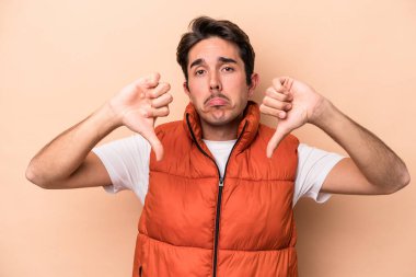 Beyazlı genç bir adam bej arka planda izole edilmiş, hoşlanmadığı bir hareket sergiliyor, kabul etmiyor. Anlaşmazlık konsepti.