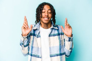 Genç Afro-Amerikalı adam mavi arka planda izole edilmiş şans diliyor.