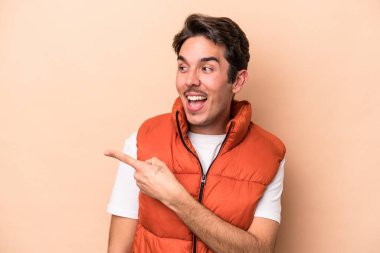 Beyaz tenli, bej arka planda izole bir genç. Gülümsüyor, neşeli ve keyifli görünüyor..