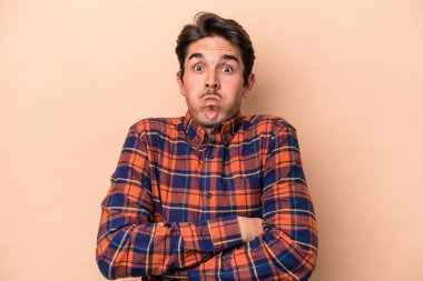 Beyazların arka planında izole edilmiş genç beyaz adamın yanakları şişer, yorgun bir ifadesi vardır. Yüz ifadesi kavramı.