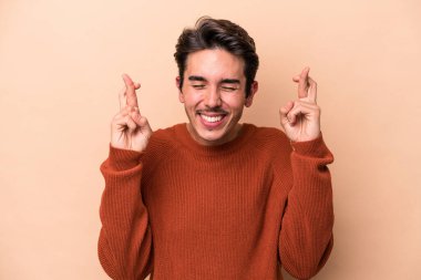 Beyazlı genç adam bej arka planda izole edilmiş şans dilemek için şans diliyor.