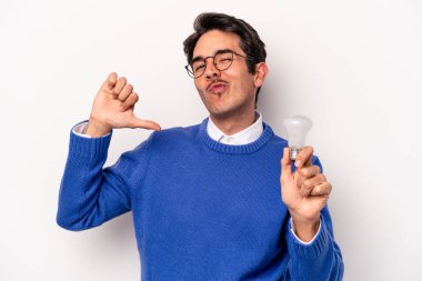 Beyaz arka planda izole edilmiş bir ampul tutan genç beyaz bir adam gururlu ve kendinden emin hissediyor, örnek olarak.