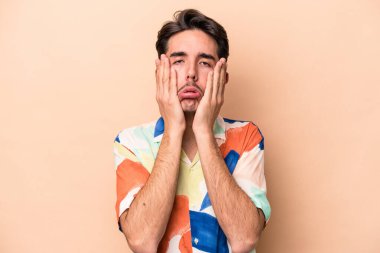 Beyaz tenli genç adam bej arka planda izole edilmiş sızlanıyor ve ağlıyordu..