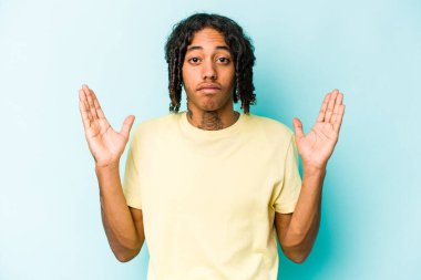 Genç Afrikalı Amerikalı adam mavi arka planda izole edilmiş. Elinde parmakları olan, gülümseyen ve kendinden emin bir şey var..