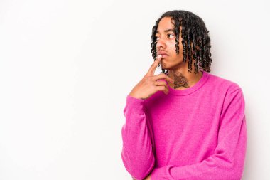 Beyaz arka planda izole edilmiş genç Afrikalı Amerikalı şüpheli ve şüpheci bir ifadeyle yana bakıyor..