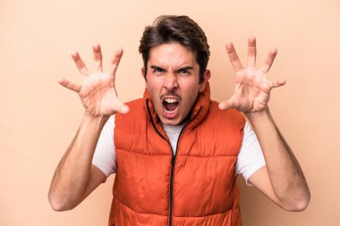 Beyazlı genç bir adam bej arka planda izole edilmiş pençelerini kedi taklidi yaparken gösteriyor, agresif bir hareket..