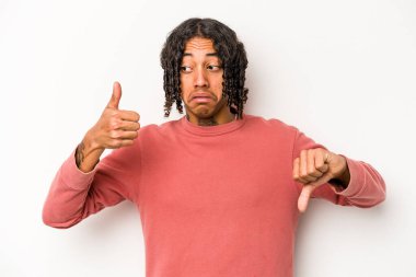 Beyaz arka planda izole edilmiş genç Afro-Amerikalı adam baş parmağını kaldırıyor ve baş parmağını aşağı gösteriyor, zor seçim konsepti