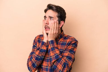 Beyazlı genç adam bej arka planda izole edilmiş korkmuş ve korkmuş..