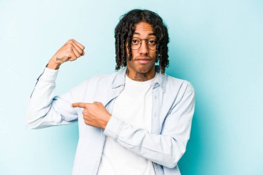 Mavi arka planda izole edilmiş genç Afro-Amerikan erkeği güçlü bir hareket sergiliyor, kadınsı gücün sembolü.
