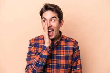 Beyazlı genç adam bej arka planda izole edilmiş ve heyecanlı bir şekilde bağırıyor..