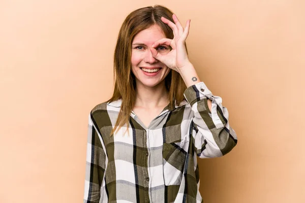 Young English woman isolated on beige background excited keeping ok gesture on eye.